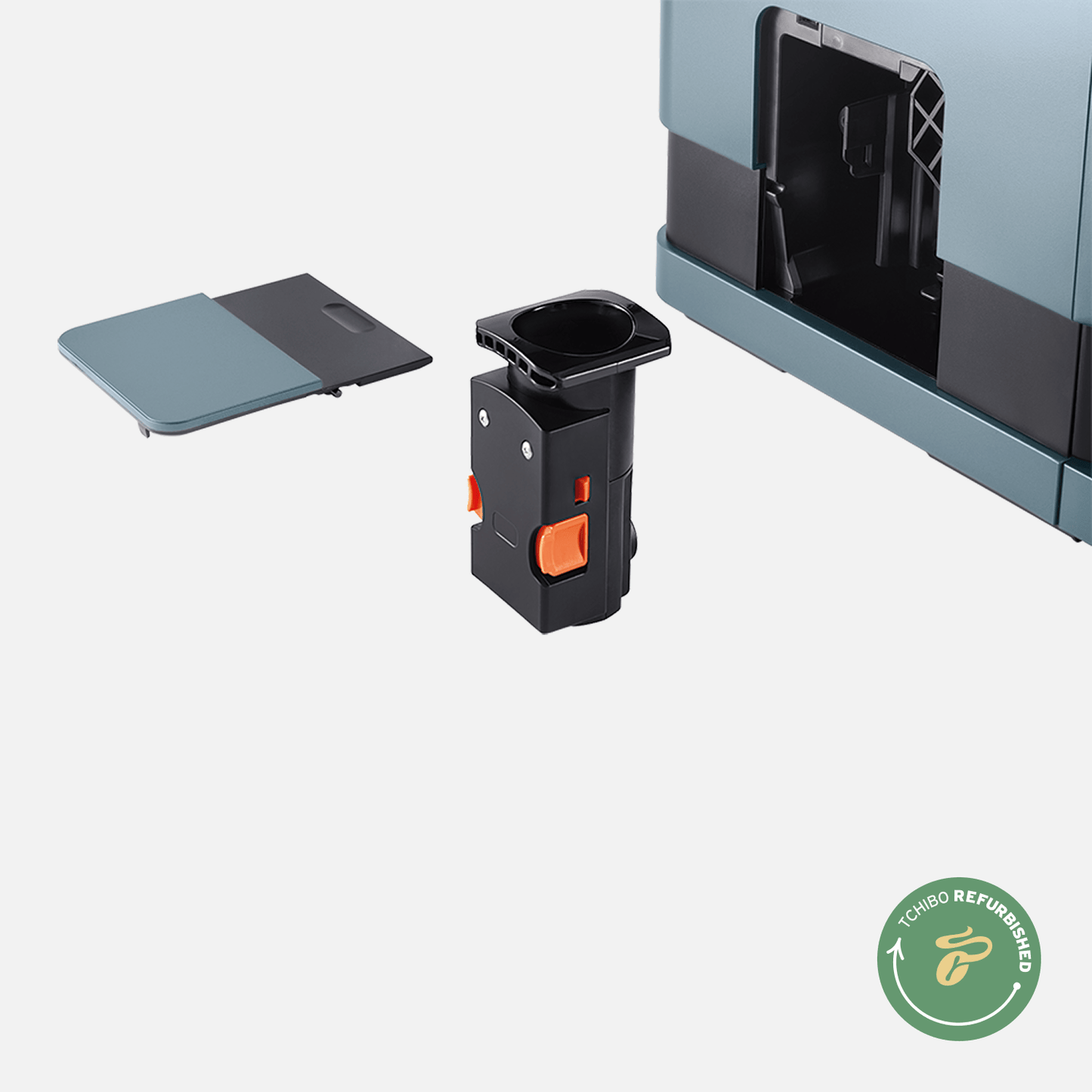 Nahaufnahme der Brühgruppe des Tchibo Esperto Caffè in Ice Blue. Die Maschine ist im Hintergrund leicht erkennbar, und die abnehmbare Seitenklappe liegt daneben.