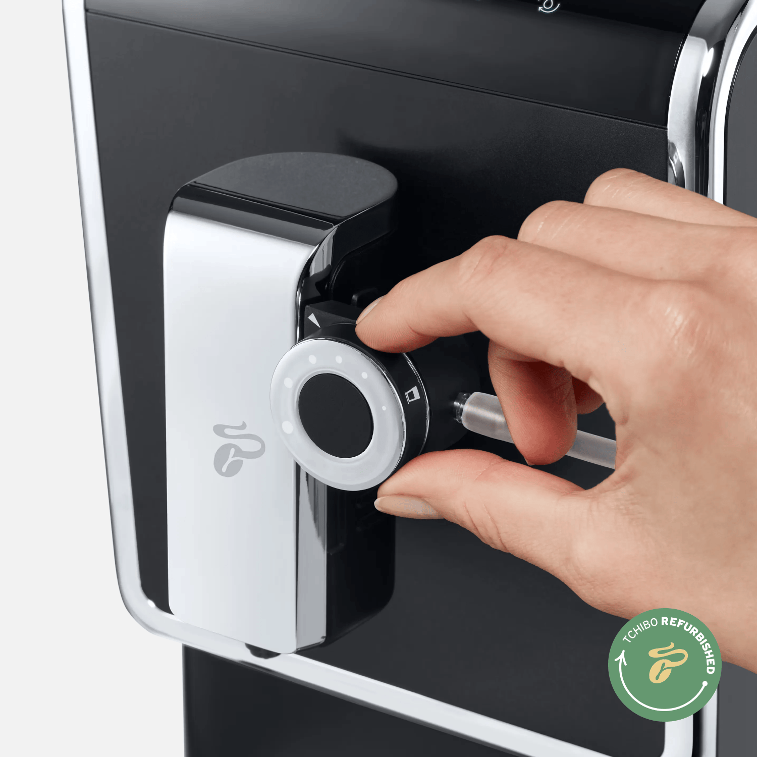 Hand bedient Drehregler am Tchibo Esperto Pro Kaffeevollautomaten mit "Tchibo Refurbished"-Logo