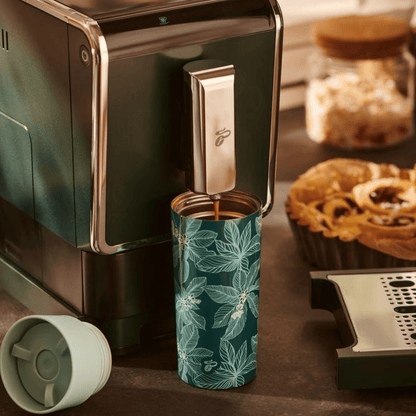 Nahaufnahme des Tchibo Esperto Caffè in Dark Green, bei dem die Abtropfschale entfernt wurde. Ein großer To-go-Becher steht unter dem Auslauf während gerade ein Kaffee gebrüht wird.