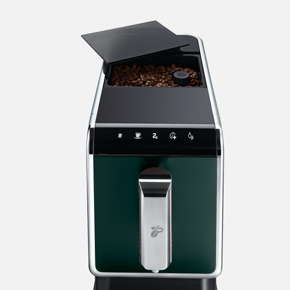 Nahaufnahme der Oberseite des Tchibo Esperto Caffè in Dark Green, mit leicht geöffnetem Deckel des Bohnenfachs, durch den Kaffeebohnen sichtbar sind.