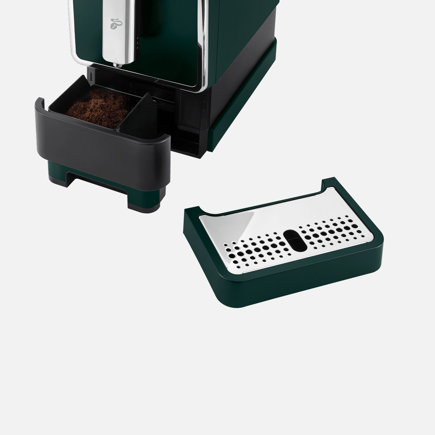 Nahaufnahme des herausgezogenen Abfallbehälters für Kaffeepulver beim Tchibo Esperto Caffè in Dark Green, der mit Kaffeepulver gefüllt ist. Die Abtropfschale liegt schräg davor.