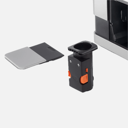 Nahaufnahme der Brühgruppe des Tchibo Esperto Caffè in Silver. Die Maschine ist im Hintergrund leicht erkennbar, und die abnehmbare Seitenklappe liegt daneben.